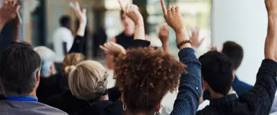 Employees raising hands to ask a question during the First Annual Employee Briefing